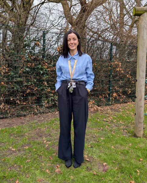 Rebecca stood against wooded background