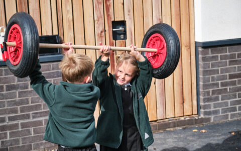 Boy and girl lifting stick and wheel
