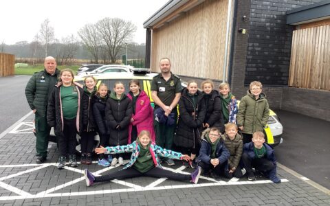 Children stood with paramedic, in front of an ambulance car.